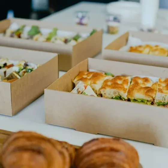 Corporate catering boxed in kraft trays, ready to leave the kitchen for an office delivery